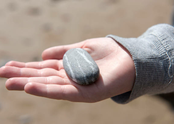 Close Up Image Of Young Boys Hand Holding Pebbles From A Beach